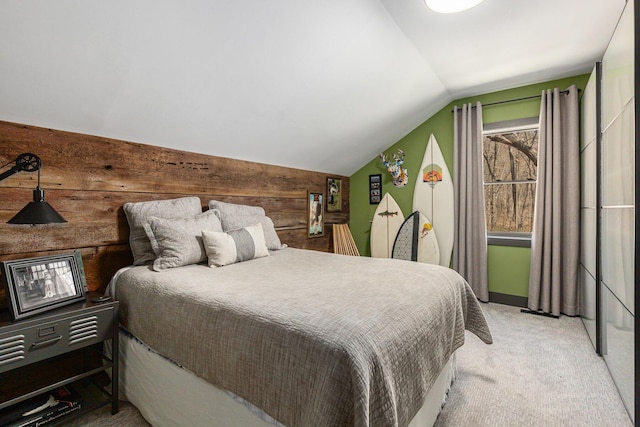 bedroom with lofted ceiling, light colored carpet, and wooden walls