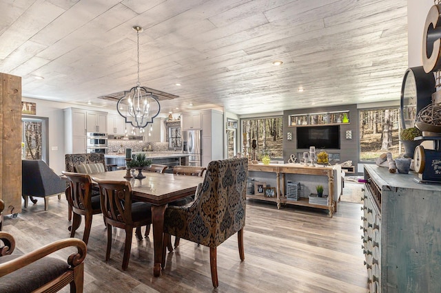 dining room featuring an inviting chandelier, light wood finished floors, and wood ceiling