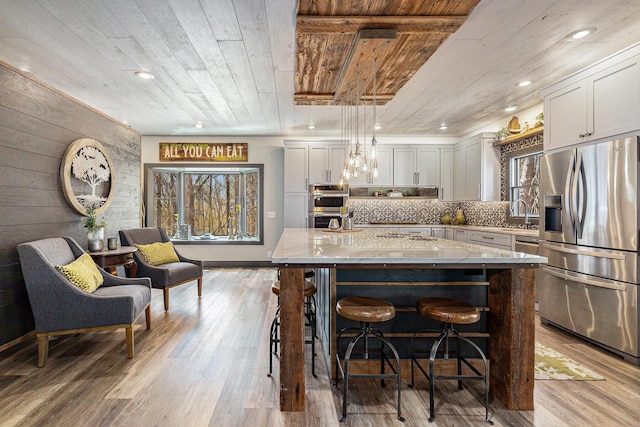 kitchen with light stone countertops, appliances with stainless steel finishes, a wealth of natural light, and wood ceiling