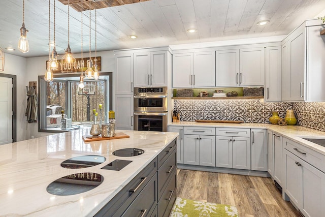 kitchen featuring light wood finished floors, stainless steel double oven, gray cabinets, light stone counters, and wood ceiling