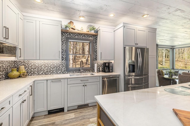 kitchen featuring a sink, appliances with stainless steel finishes, visible vents, light wood finished floors, and backsplash