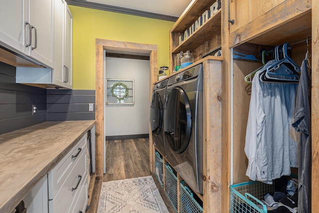 washroom with dark wood-type flooring, separate washer and dryer, and cabinet space