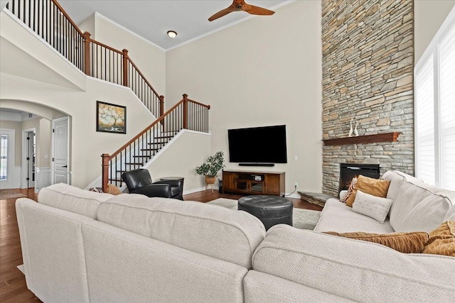 living area featuring wood finished floors, a ceiling fan, stairs, and a high ceiling