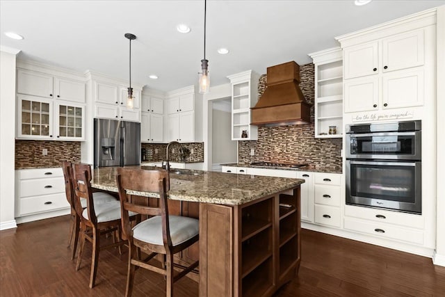 kitchen with decorative backsplash, open shelves, custom range hood, a sink, and stainless steel appliances