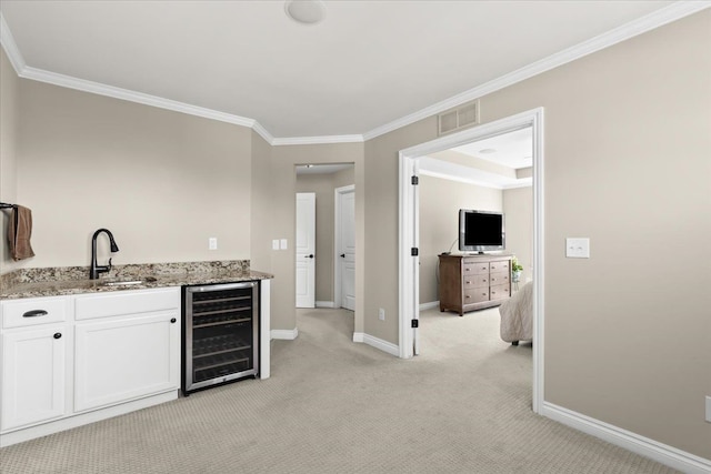 bar featuring light carpet, beverage cooler, baseboards, visible vents, and ornamental molding