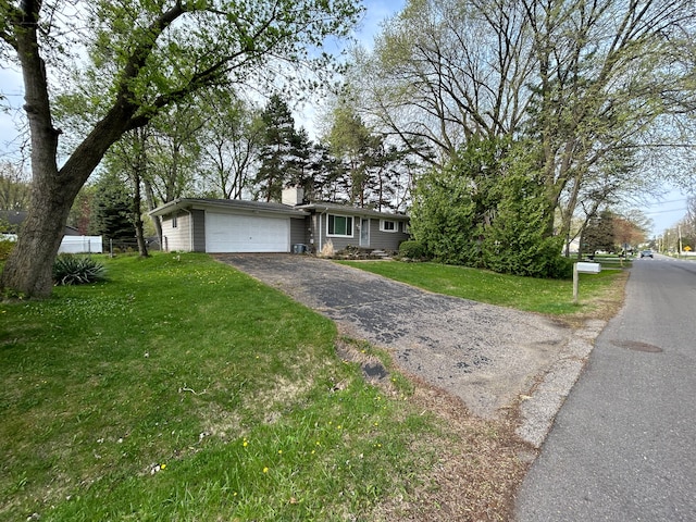 view of front of home with an attached garage, a chimney, a front lawn, and aphalt driveway