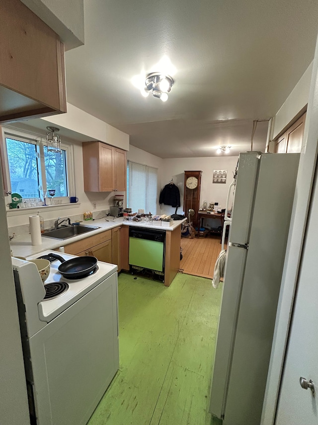 kitchen featuring a sink, light countertops, light wood finished floors, a peninsula, and white appliances