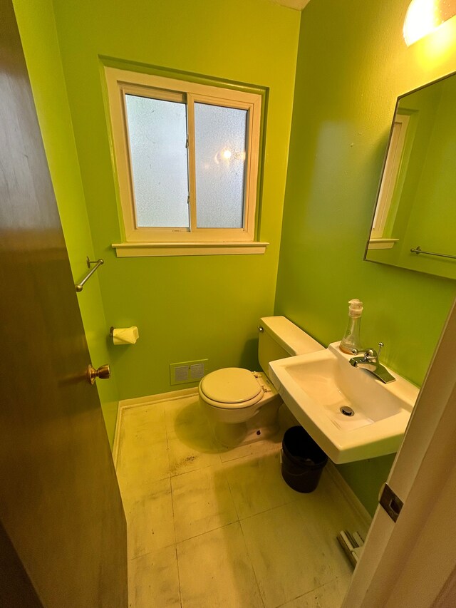 half bath featuring a sink, tile patterned floors, and toilet