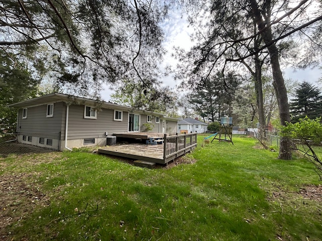 rear view of property with a playground, fence, a yard, and a wooden deck
