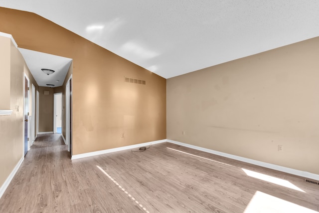 unfurnished room featuring visible vents, baseboards, wood finished floors, and vaulted ceiling