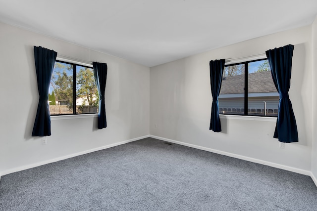carpeted spare room featuring baseboards and visible vents
