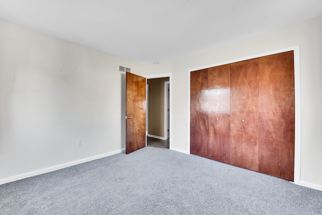 unfurnished bedroom featuring carpet floors, baseboards, a closet, and visible vents