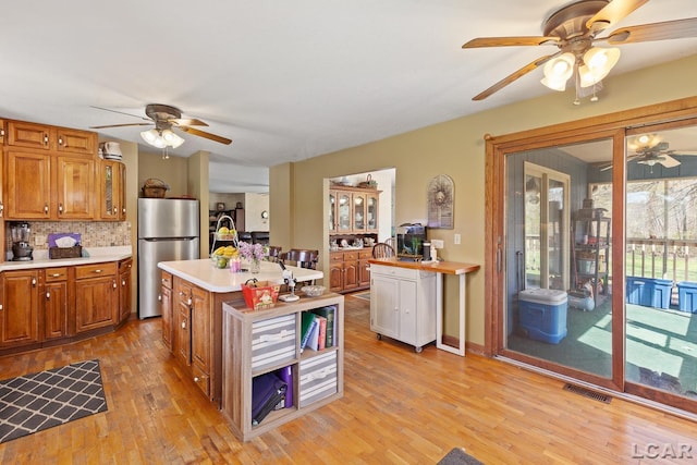 3620 Sharp Rd, Adrian, MI 49221 - kitchen with freestanding refrigerator, decorative backsplash, ceiling fan, light countertops, and brown cabinets