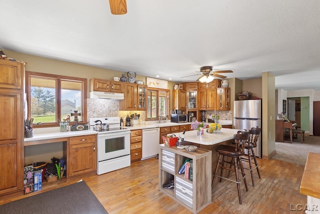 3620 Sharp Rd, Adrian, MI 49221 - kitchen featuring brown cabinetry, light countertops, appliances with stainless steel finishes, and under cabinet range hood