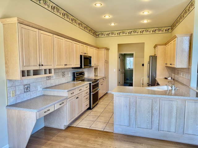 8505 Woodridge Dr, Davison, MI 48423 - kitchen with a peninsula, a sink, appliances with stainless steel finishes, and decorative backsplash