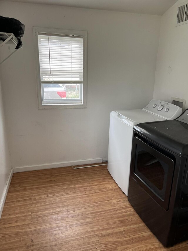 laundry room featuring independent washer and dryer, visible vents, baseboards, light wood-type flooring, and laundry area