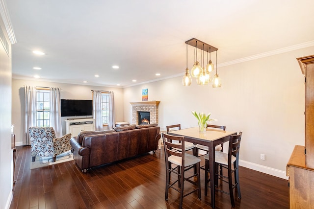 dining space with dark wood finished floors, ornamental molding, and a fireplace
