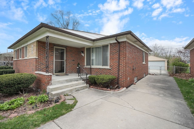 view of front of home with a detached garage, fence, and brick siding