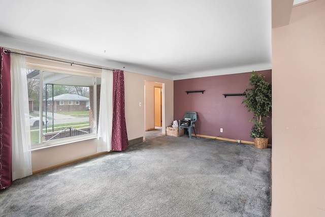 unfurnished living room with baseboards and carpet flooring