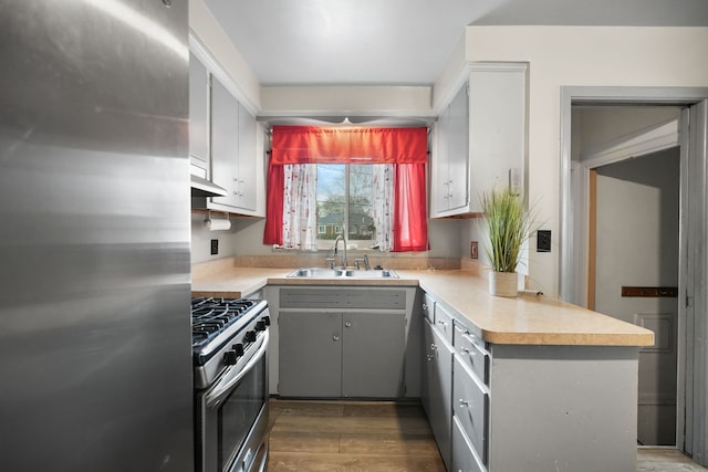 kitchen featuring a sink, light countertops, gray cabinets, stainless steel appliances, and under cabinet range hood