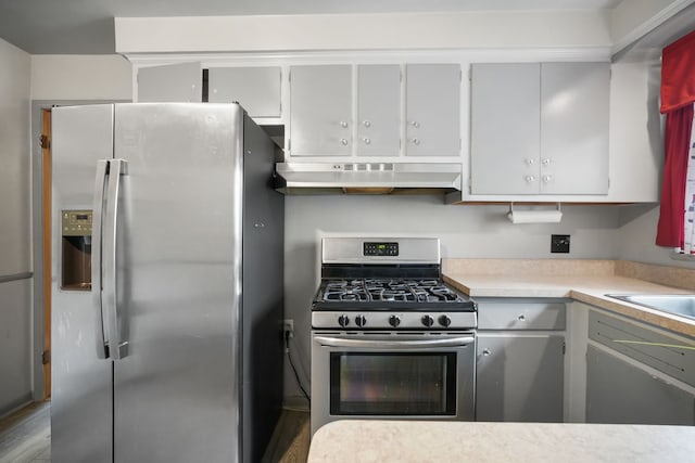 kitchen with light countertops, stainless steel appliances, wood finished floors, and under cabinet range hood