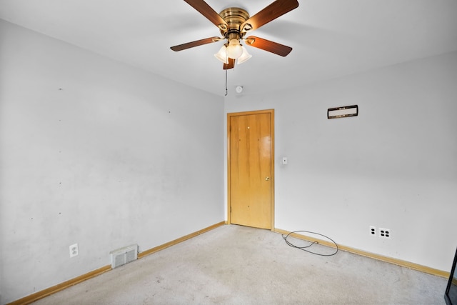 empty room with baseboards, light carpet, a ceiling fan, and visible vents