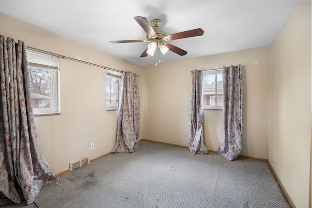 carpeted spare room featuring baseboards, a ceiling fan, and visible vents