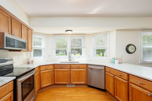44492 Midway Dr, Novi, MI 48375 - kitchen featuring stainless steel appliances, a sink, light wood-style flooring, brown cabinets, and light stone counters