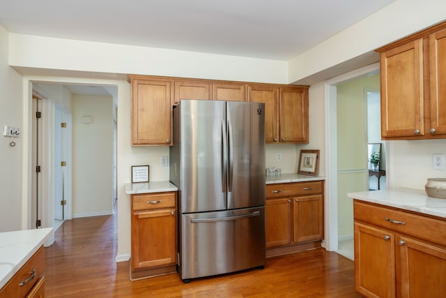 44492 Midway Dr, Novi, MI 48375 - kitchen with freestanding refrigerator, wood finished floors, brown cabinets, and light stone counters