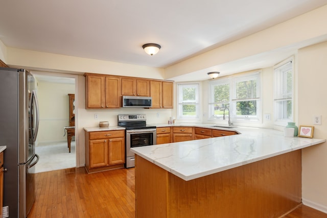 44492 Midway Dr, Novi, MI 48375 - kitchen featuring stainless steel appliances, a peninsula, a sink, brown cabinetry, and light stone counters