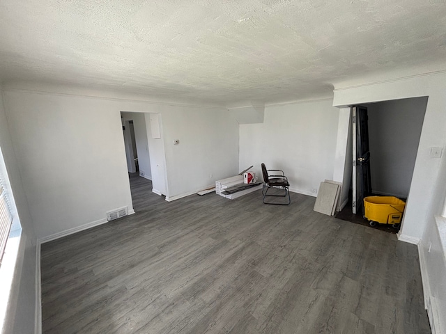 spare room featuring baseboards, dark wood-style floors, a textured ceiling, and visible vents
