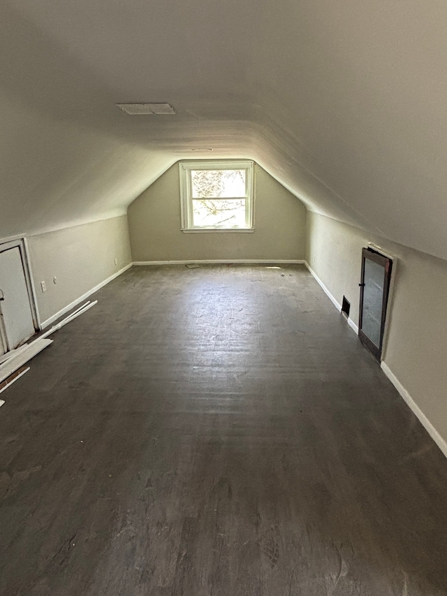 additional living space with baseboards, wood finished floors, and lofted ceiling