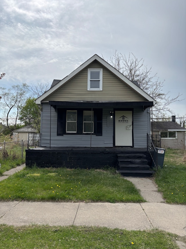 bungalow-style home featuring fence, covered porch, and a front lawn