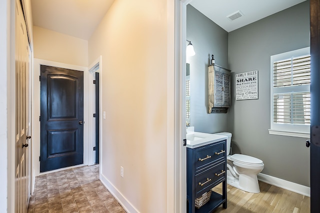 bathroom with toilet, visible vents, vanity, and baseboards