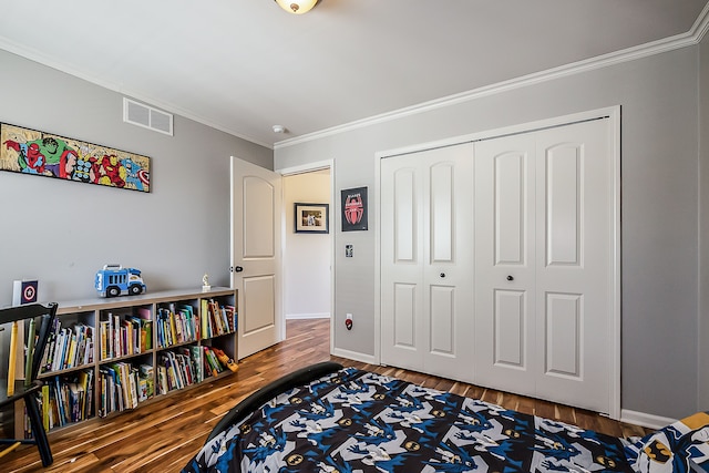 bedroom with crown molding, a closet, visible vents, and wood finished floors