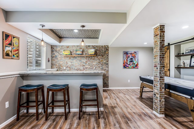 bar with a barn door, a tray ceiling, baseboards, pendant lighting, and wood finished floors