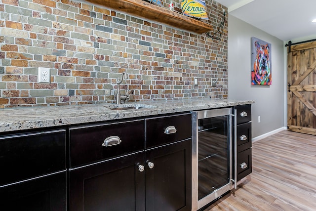 interior space featuring a sink, a barn door, baseboards, wine cooler, and wet bar