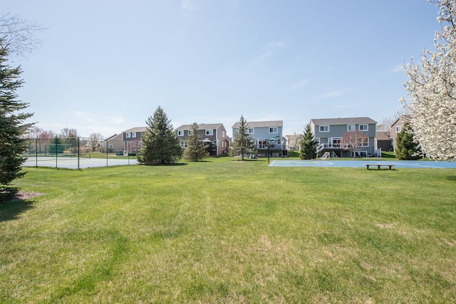 view of yard with a residential view, community basketball court, and fence