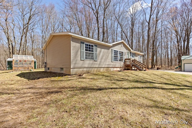 view of side of home with a garage, an outdoor structure, a greenhouse, and a yard
