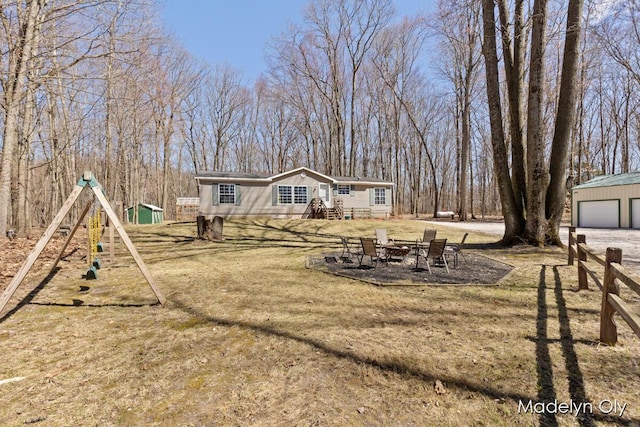 view of yard with an outdoor structure, a detached garage, and a playground