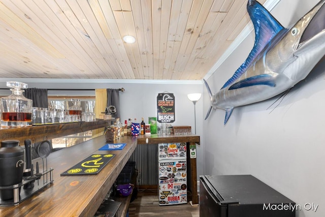 bar featuring ornamental molding, wooden ceiling, a bar, and wood finished floors