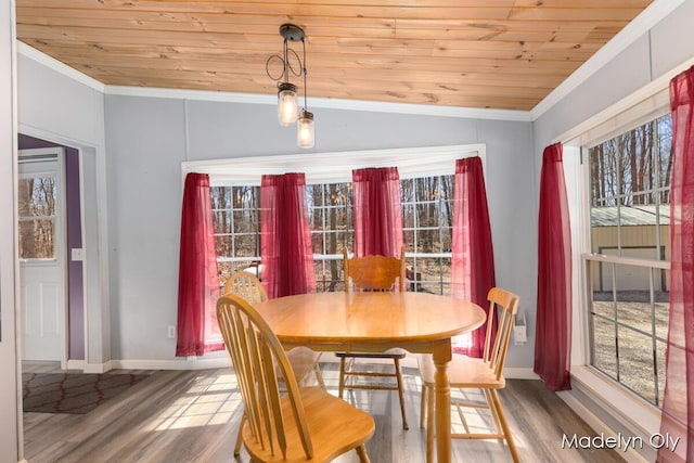 dining room featuring ornamental molding, a healthy amount of sunlight, wood finished floors, and wood ceiling
