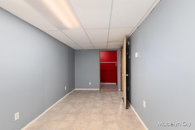 spare room featuring a drop ceiling and baseboards