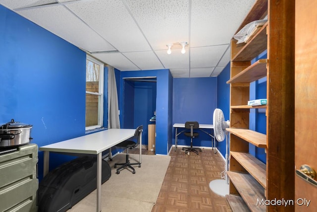 home office with baseboards and a drop ceiling