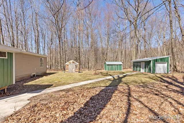 view of yard featuring a garage, a storage unit, and an outbuilding