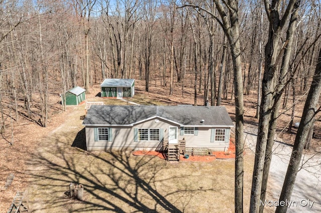 view of front of property featuring an outbuilding, a shed, and roof with shingles