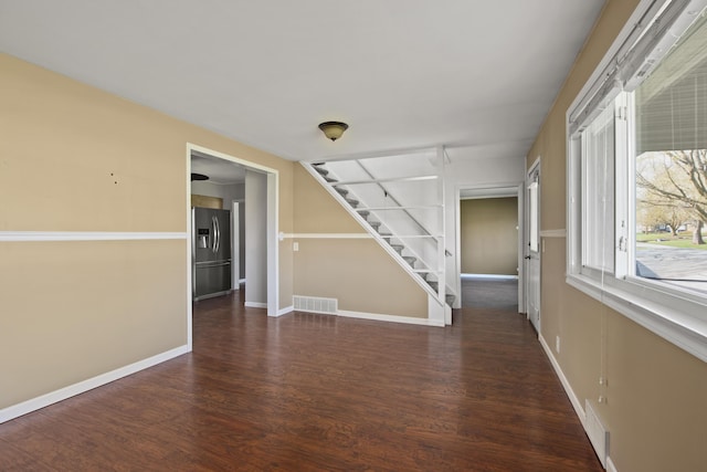 unfurnished room featuring visible vents, stairway, wood finished floors, and baseboards