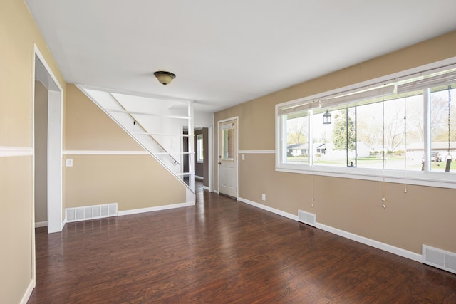 unfurnished living room with stairway, visible vents, and baseboards
