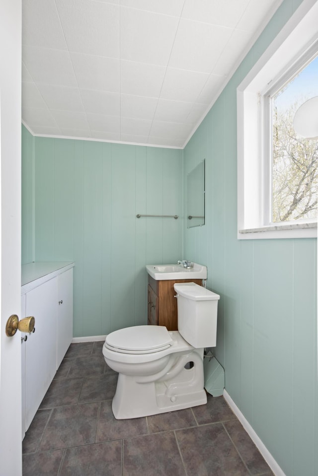 half bath with toilet, a sink, and baseboards