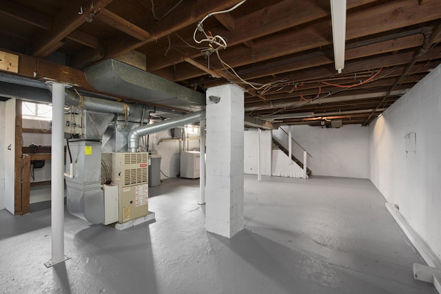 unfinished basement with heating unit, stairway, separate washer and dryer, and water heater
